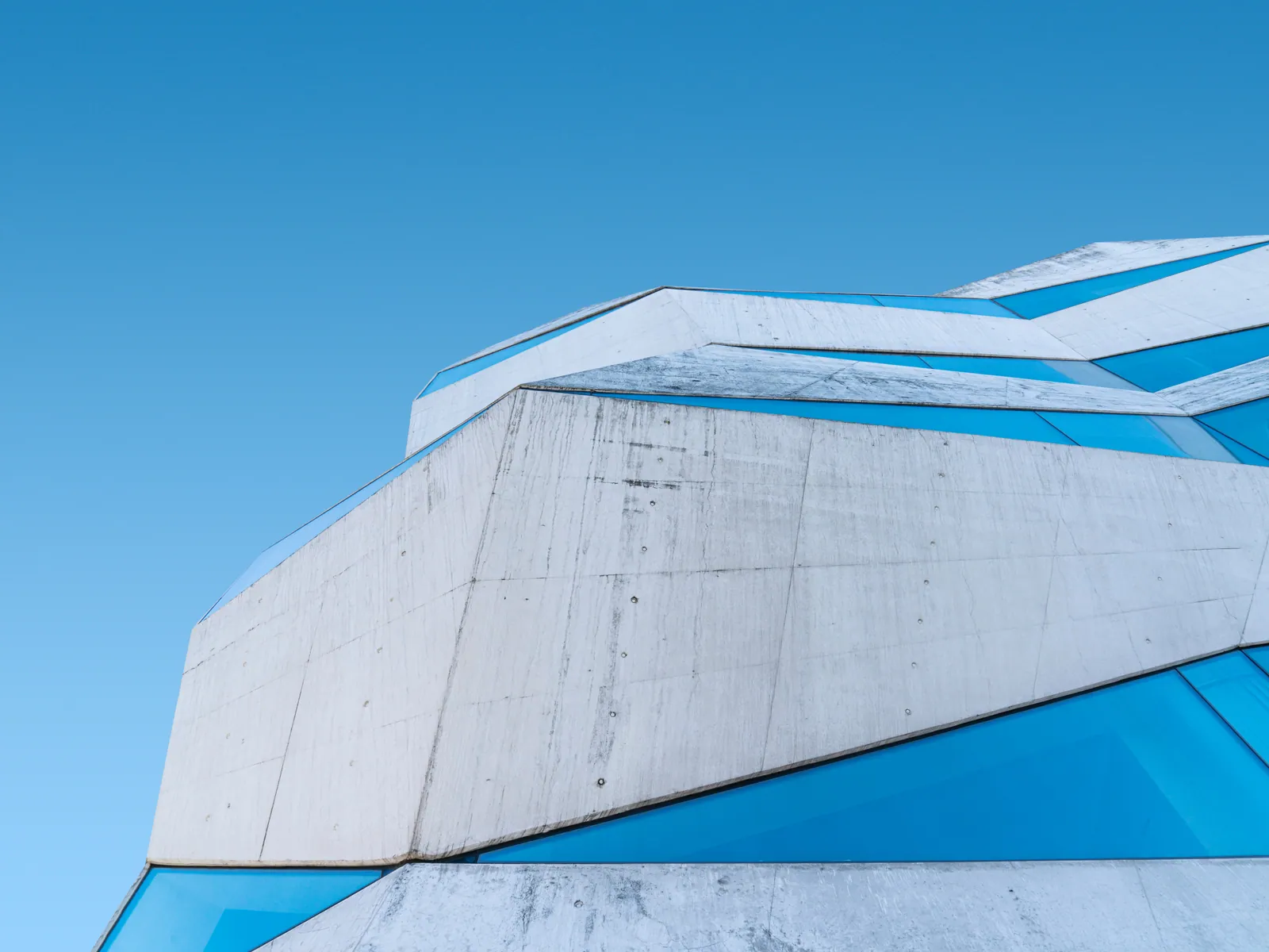 Concrete folds beside bright blue glazing