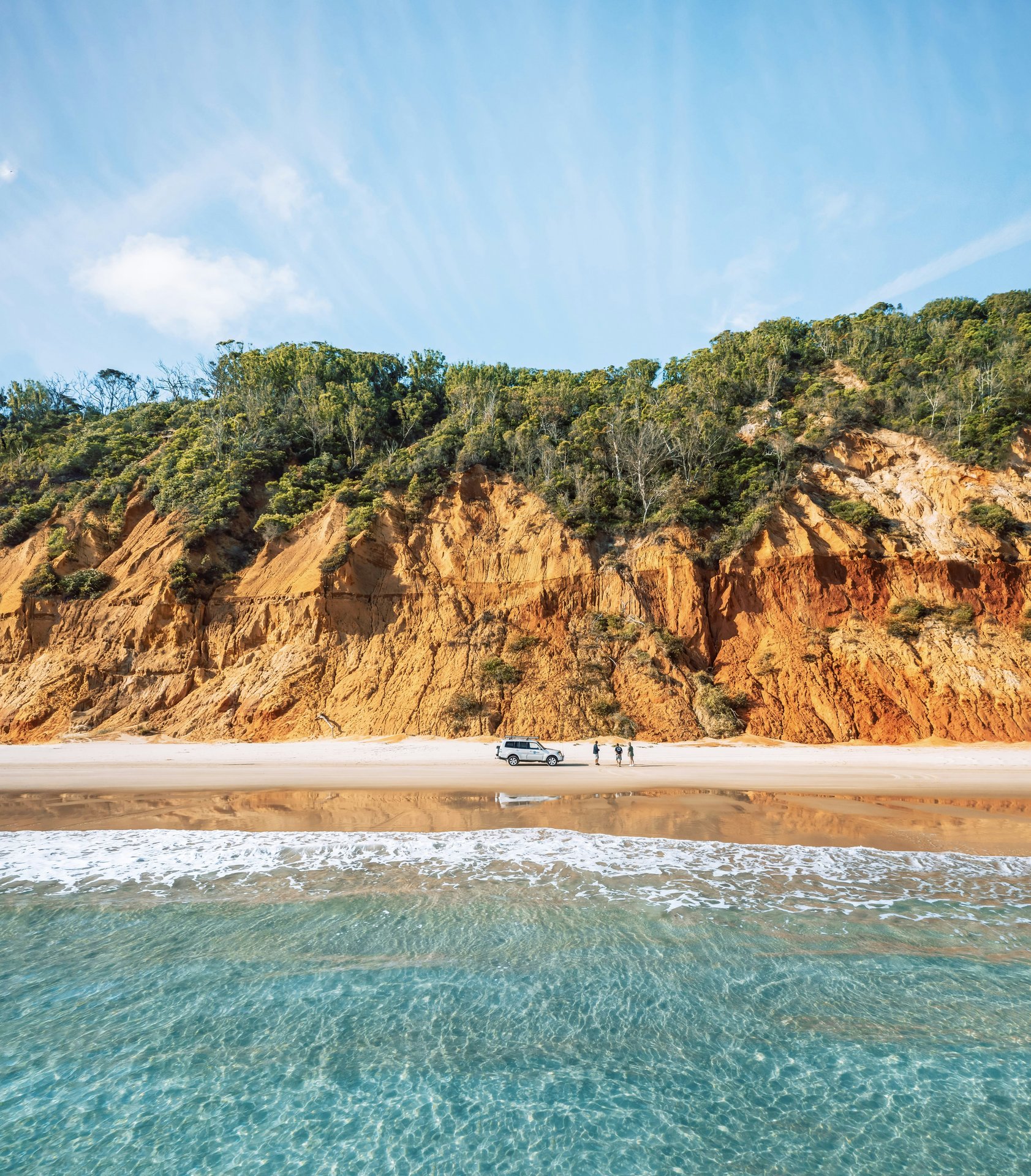 A sandy beach beneath a rugged coastal cliff