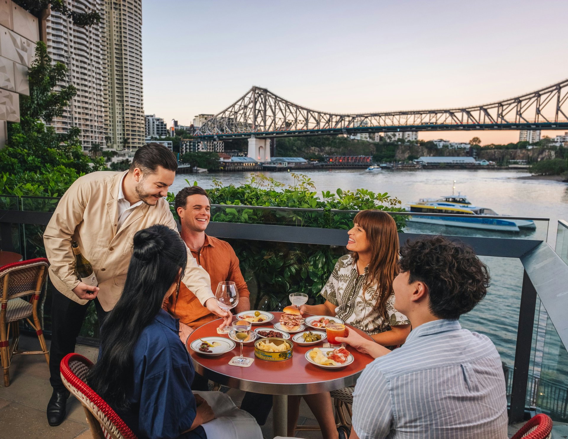 Friends sharing a meal overlooking Brisbane’s river and bridge