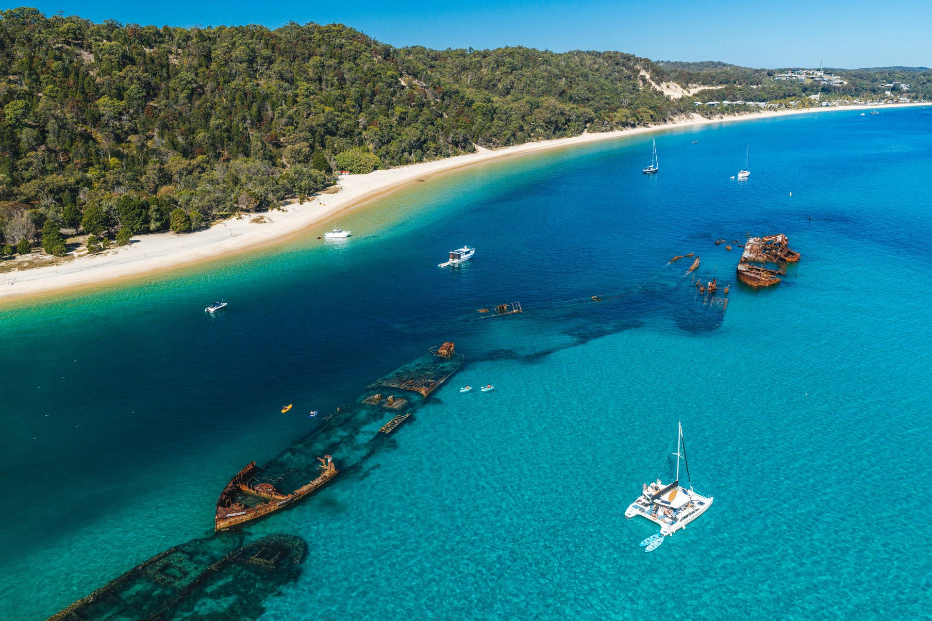 A forested Queensland coastline beside clear blue water