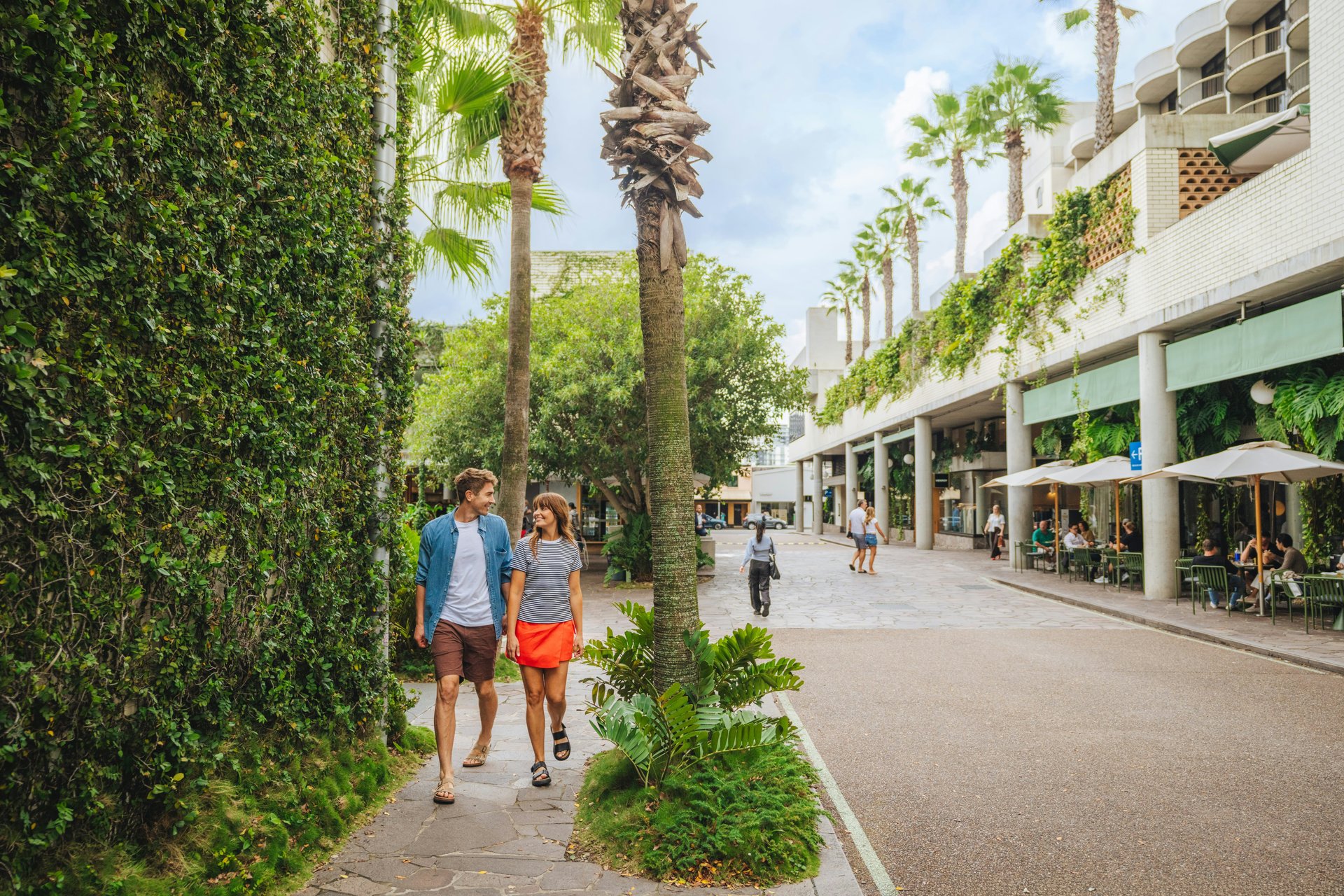 Travellers on a palm-lined shopping street