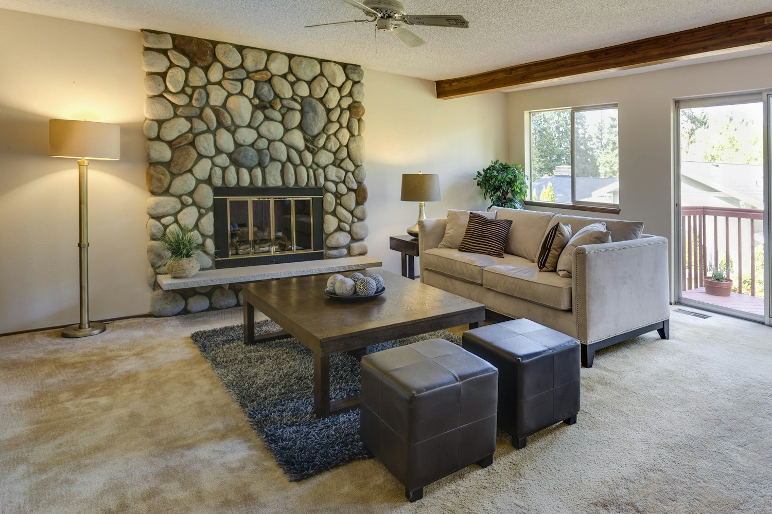 Cosy lounge with upholstered chairs, warm fabrics and a stone fireplace