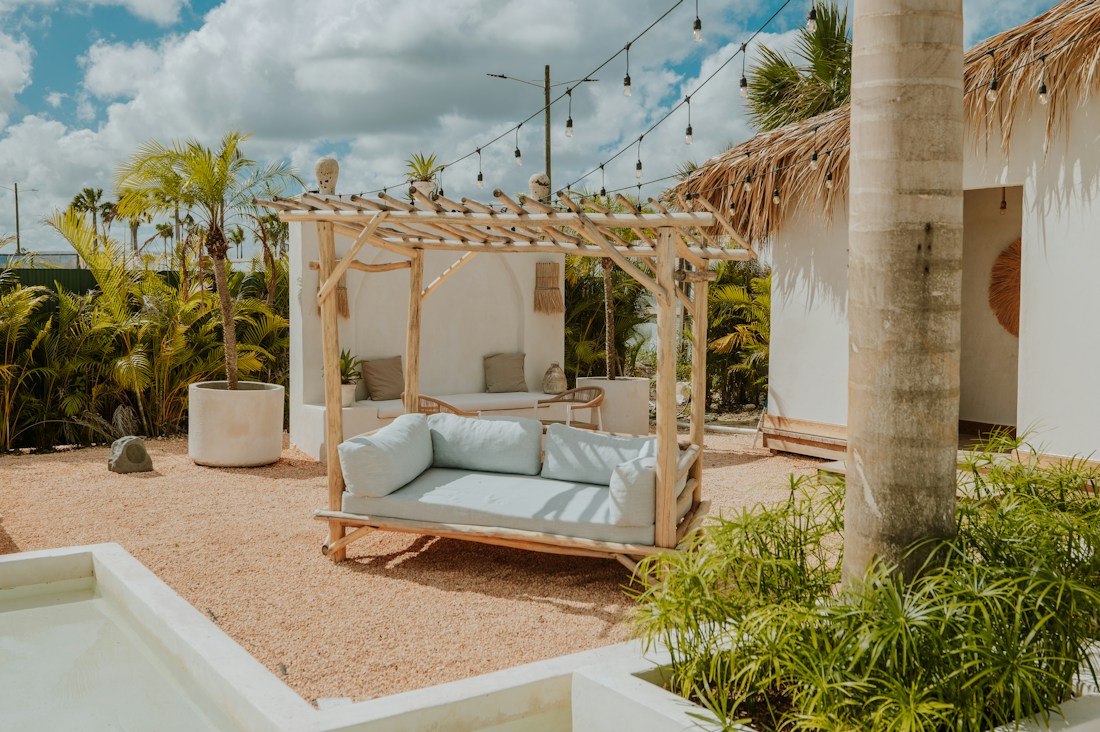 Outdoor daybed beneath a timber pergola with plants and string lights